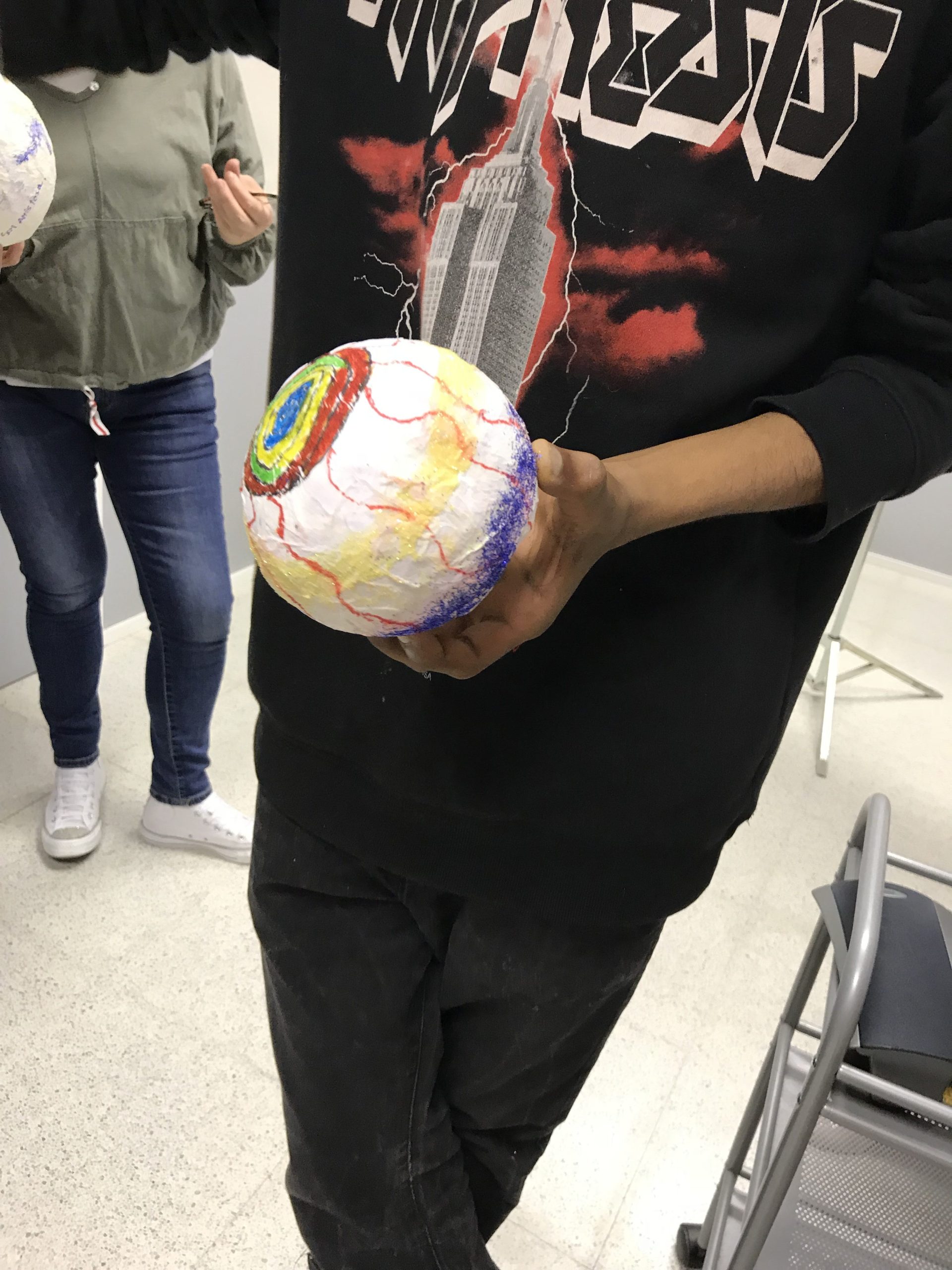 Manos sosteniendo una esfera decorada durante un taller de educación emocional para adolescentes, sin rostros visibles