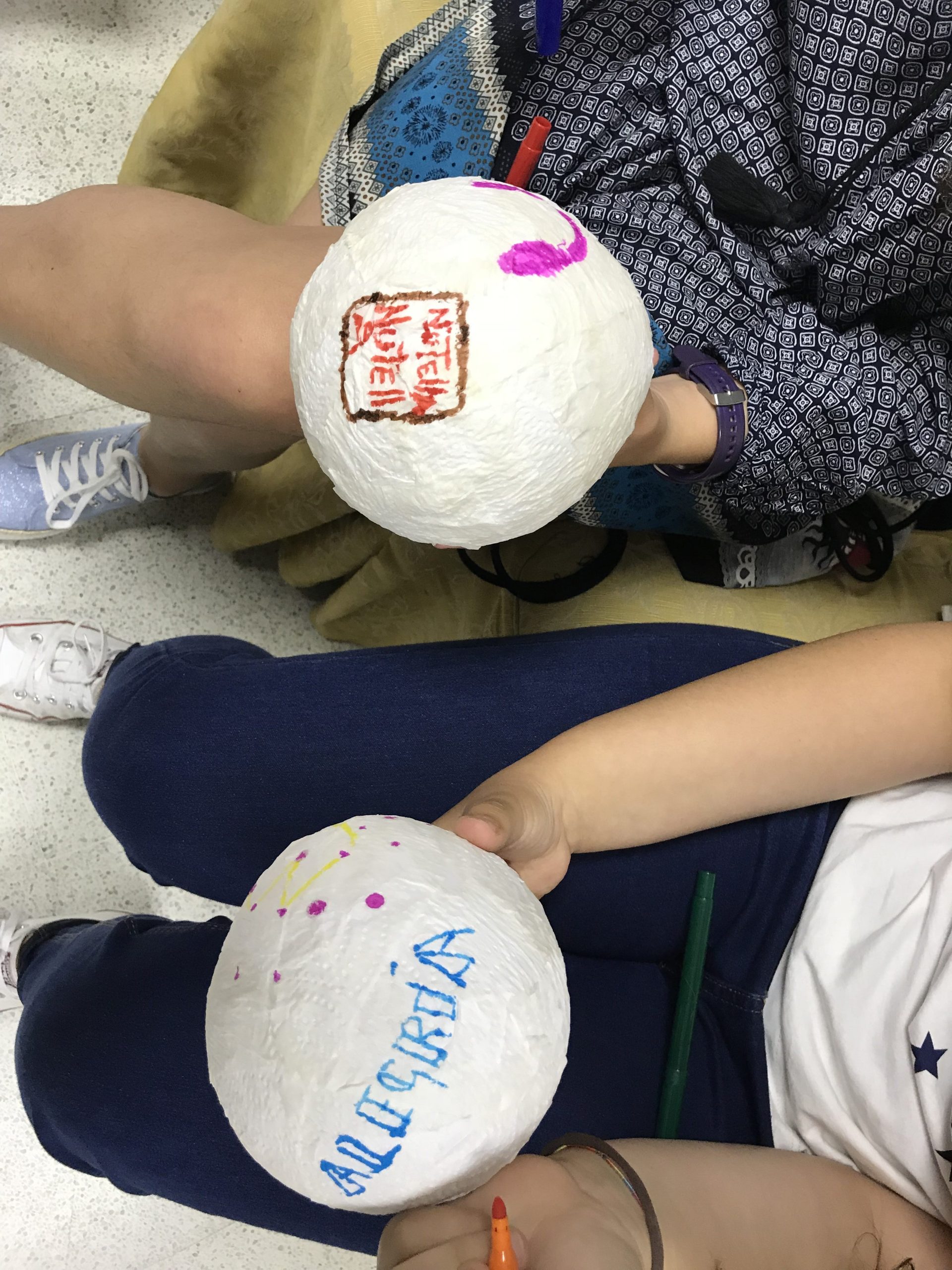 Manos y esferas decoradas en un taller creativo de educación emocional para adolescentes, sin rostros visibles