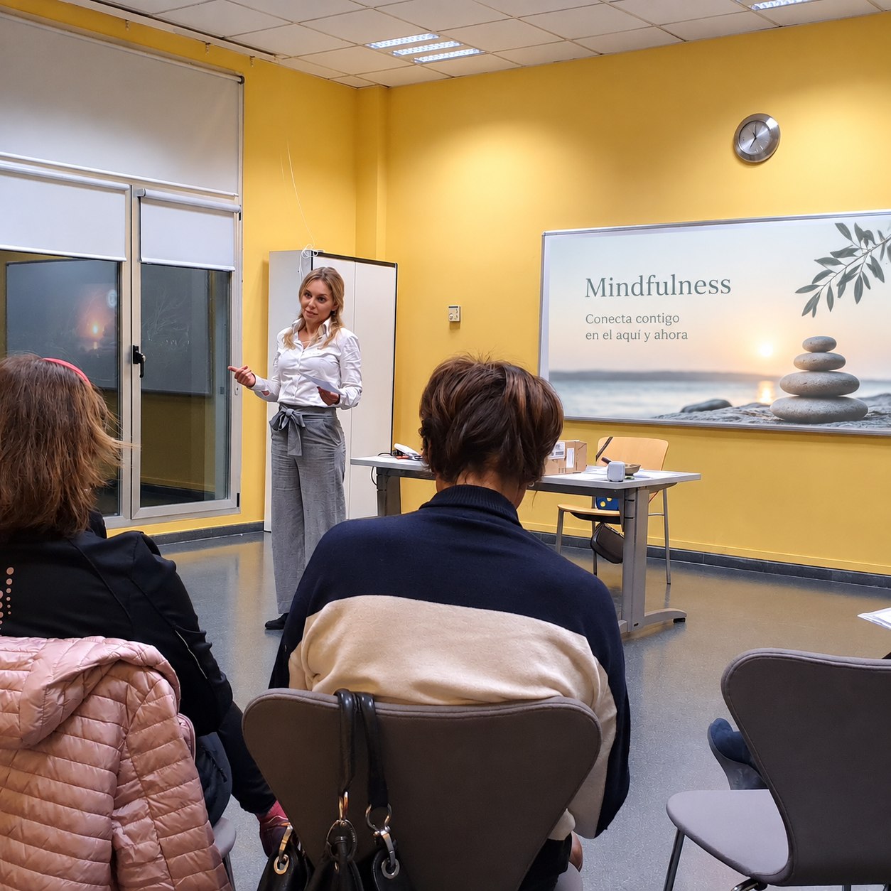 Sesión de mindfulness para adultos con una facilitadora y participantes de espaldas